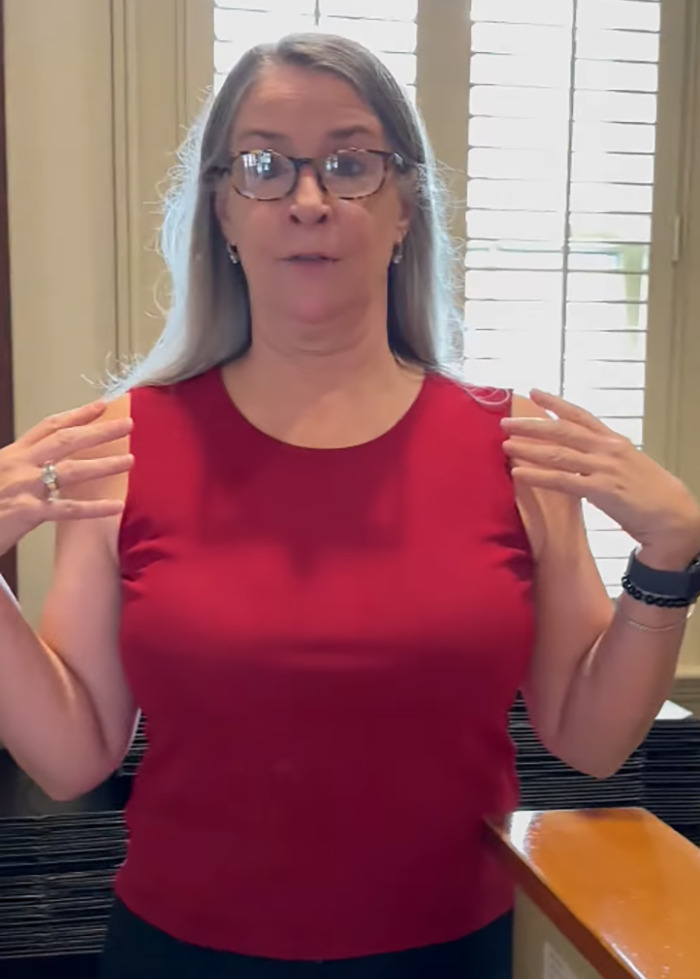 Woman gestures about outfit controversy in restaurant.