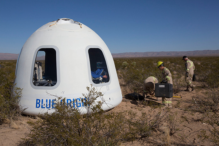 Blue Origin capsule in desert with three people inspecting, raising conspiracy theorists' "fake" claim. Blue Origin capsule in desert with three people inspecting, raising conspiracy theorists' "fake" claim.
