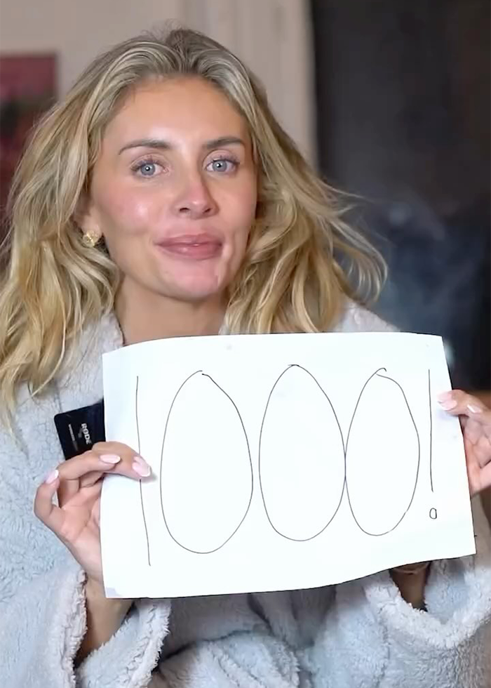 Woman holding a sign with 1000 written on it, related to Bonnie Blue escorted from major soccer stadium SEO keyword.