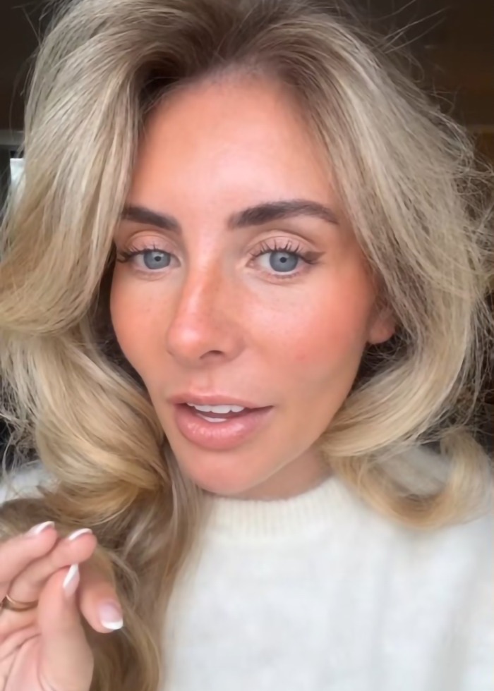 Blonde woman with blue eyes in a white sweater, speaking and gesturing, related to Bonnie Blue escorted from major soccer stadium.