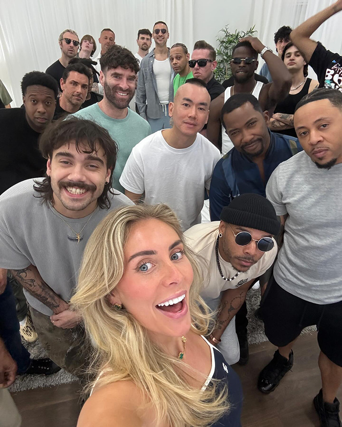Group selfie featuring a smiling woman with blonde hair and multiple men, unrelated to Bonnie Blue escorted from soccer stadium.