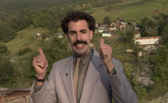 Actor in character wearing a light suit giving thumbs up outdoors, showcasing dedication in difficult roles for acting career.