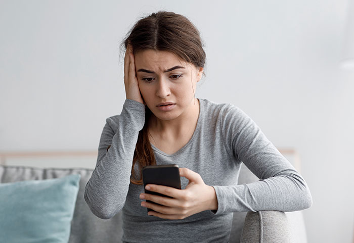 Woman looking shocked at a phone, discovering texts in an ER setting.