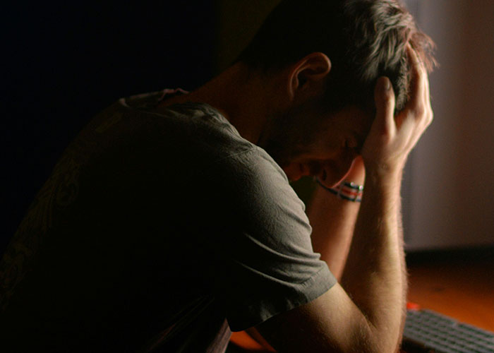 A man sitting in dim light, head in hands, reflecting on a breakup after 9 years.