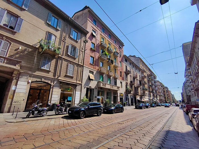 European city street with colorful buildings and parked cars on a sunny day.