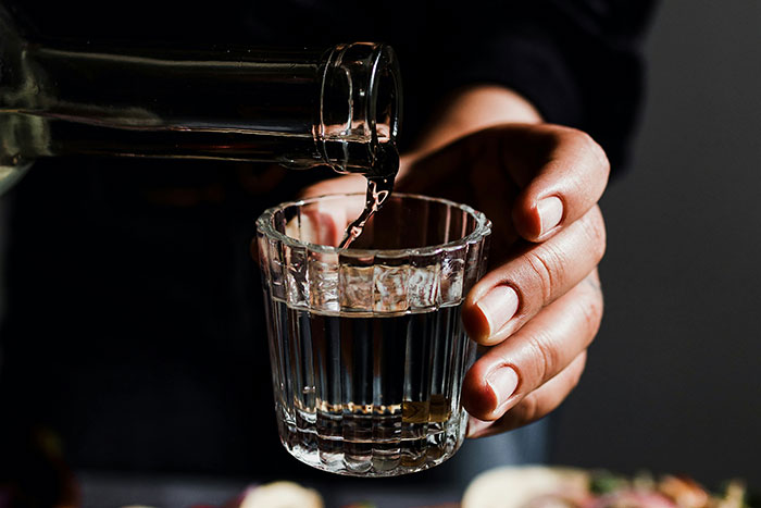 A close-up of a hand pouring water into a glass, highlighting a strange European custom.