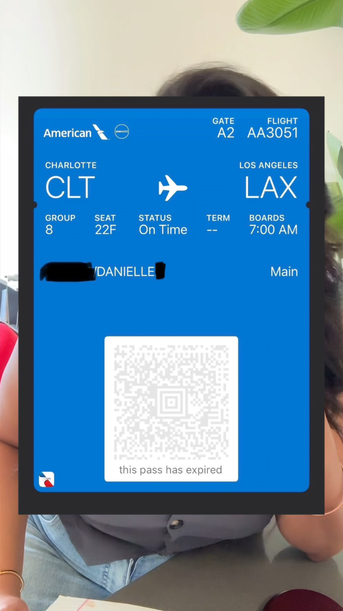 Airline boarding pass for a flight from Charlotte to Los Angeles displayed over a woman's torso.