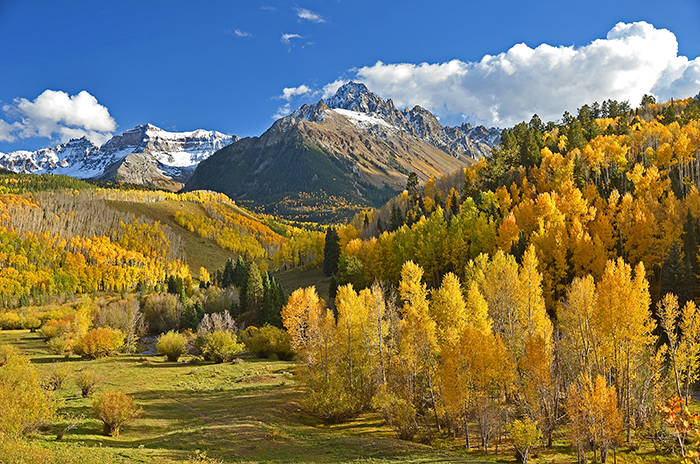 Mountain landscape with autumn trees and a clear blue sky, illustrating a serene vacation backdrop.