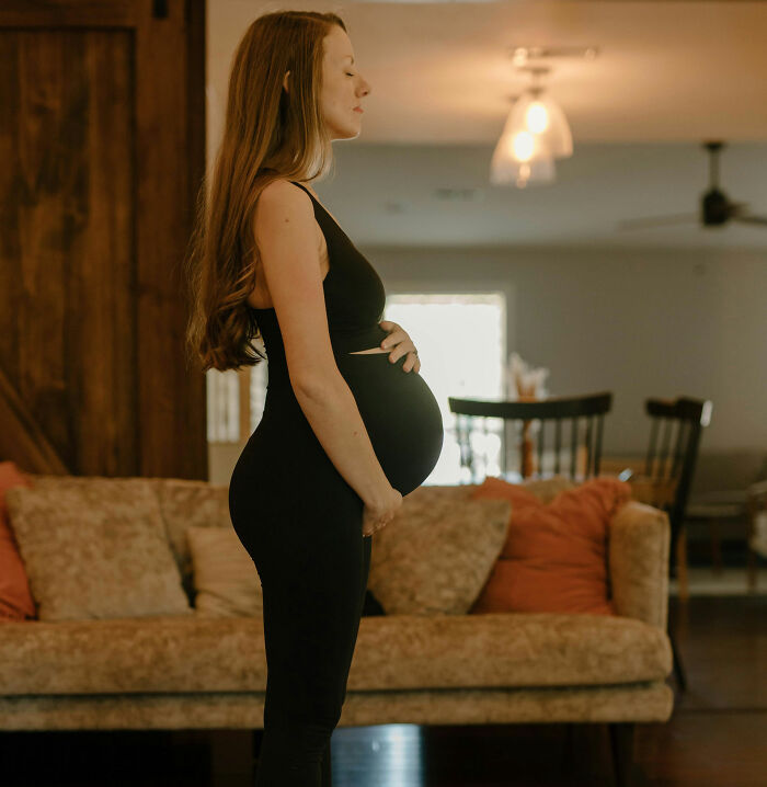 Pregnant woman standing in living room, highlighting common but underestimated trauma experiences.