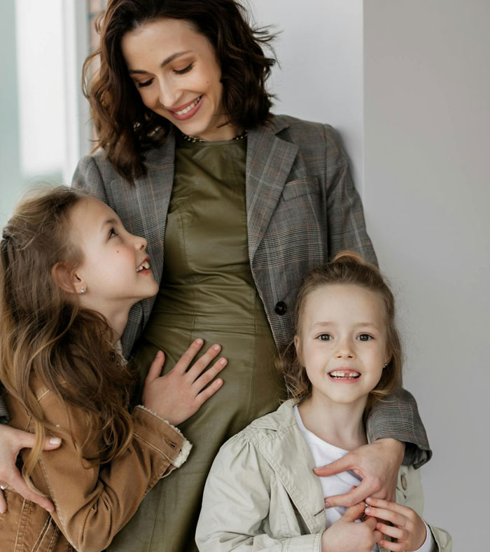 A smiling woman with two daughters, representing a spiteful accusation context.