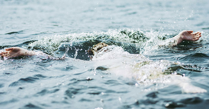 Person struggling to stay afloat in water, capturing the urgency of a drowning rescue and lifeguard intervention.
