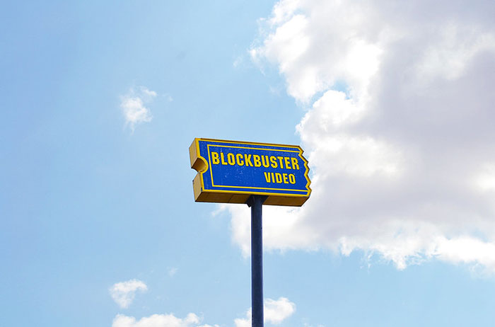 Blockbuster video sign on pole against blue sky, symbolizing companies wrecked by a single bad decision.