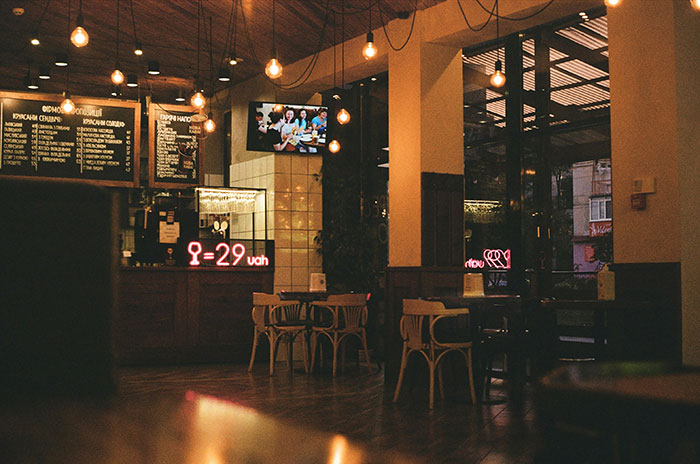 Empty cozy café interior with wooden furniture and warm lighting, illustrating companies impacted by a bad decision.