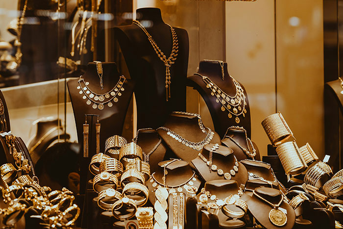 Elegant jewelry display in a store window, showcasing gold necklaces and bracelets.