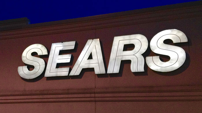 Sears store sign illuminated at night representing companies that were successful until a bad decision wrecked them completely