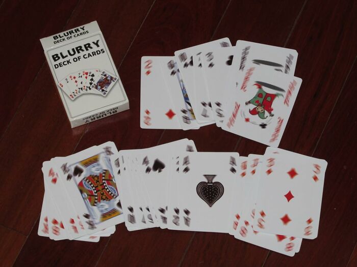 Blurry deck of cards scattered on a wooden floor, showcasing a unique and ridiculous find.
