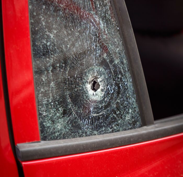 Close-up of a shattered car window with a bullet hole, illustrating impact and damage related to guys slept married woman why.