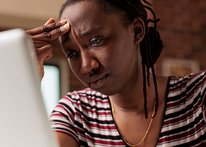 A worried individual in a striped shirt looking at a laptop, contemplating life's choices and temptations.