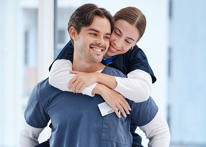 A smiling couple in blue scrubs, showcasing moments of temptation in a hospital setting.