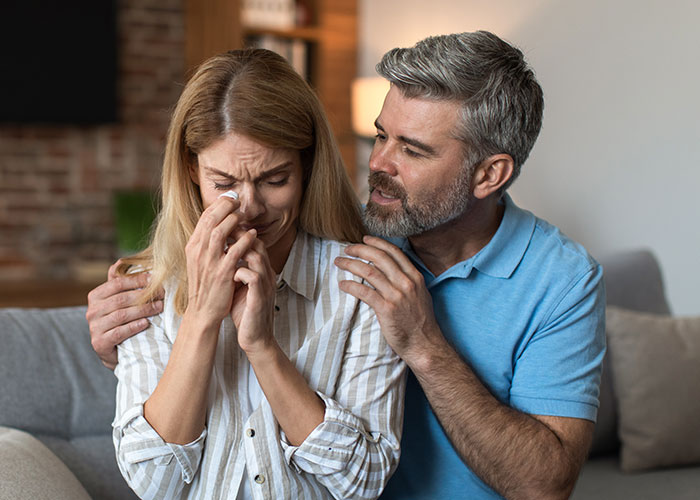 Man comforting a crying woman, highlighting effects of cheating temptation.