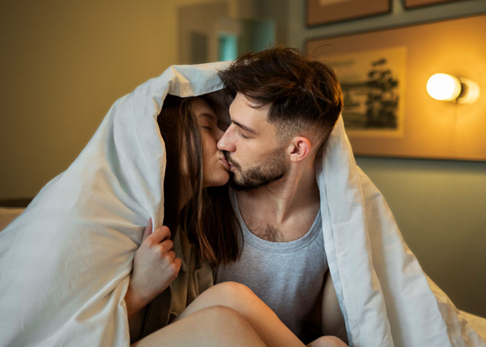 A couple kissing under a blanket, illustrating temptation leading to cheating.