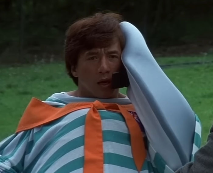 Man in costume with surprised expression, wearing striped outfit in outdoor setting.