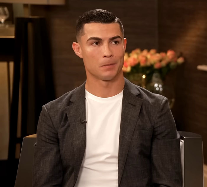 A person in a gray blazer and white shirt, sitting in an interview setting.