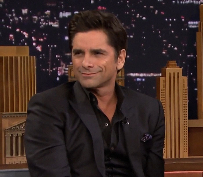 Man in a dark suit on a talk show set, illustrating the complexity of talented people.