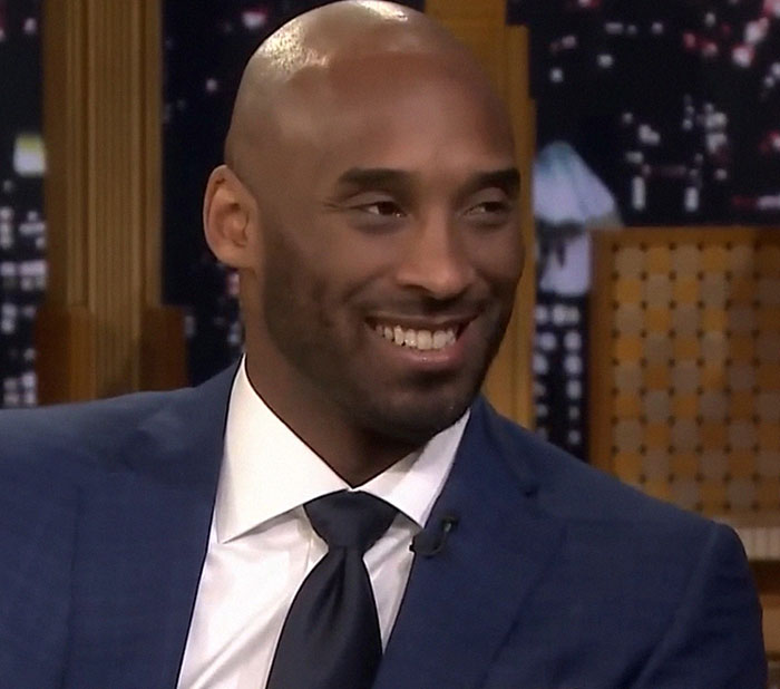 A person in a suit smiling on a talk show set, representing the duality of talented people.