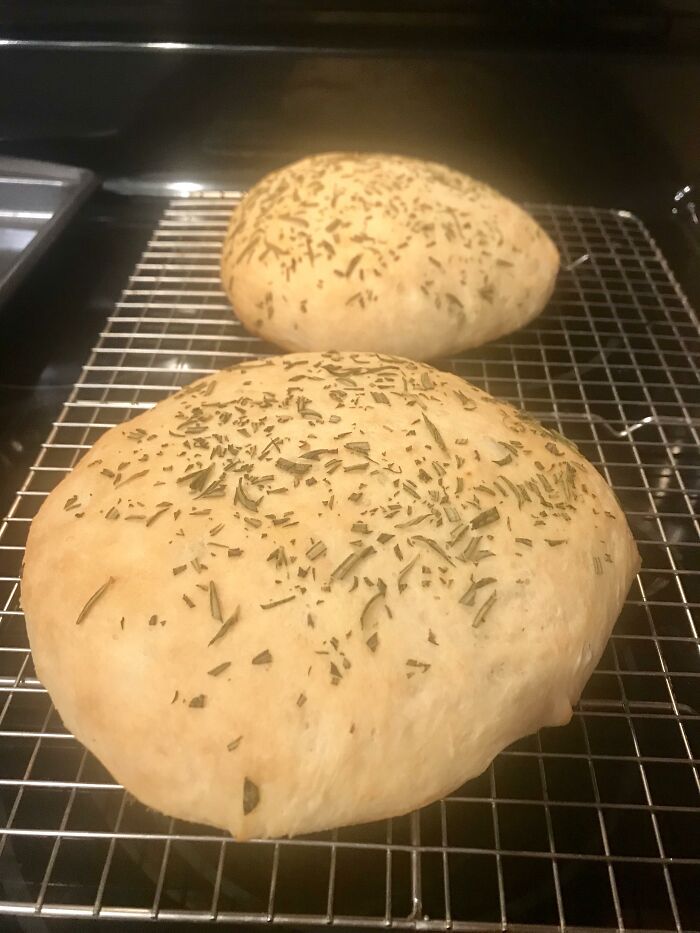 Two freshly baked rosemary breads on a cooling rack, highlighting chain restaurant baking practices.