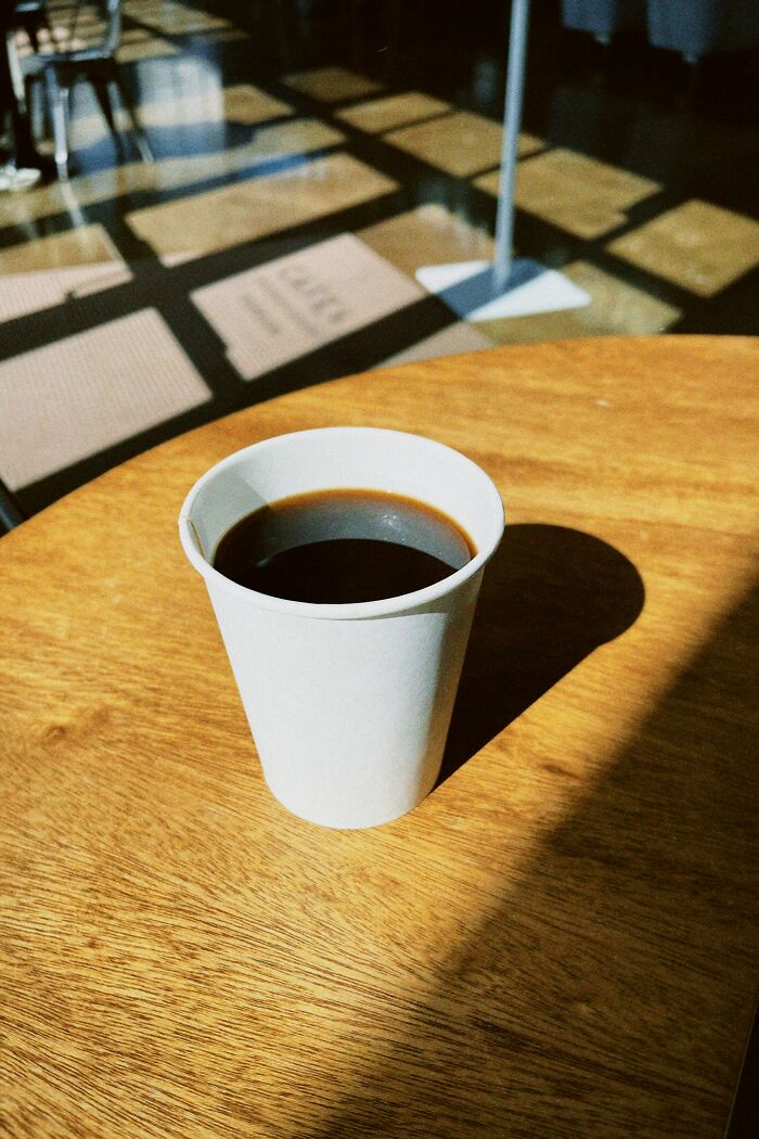 Paper cup of coffee on a wooden table in a chain restaurant setting, capturing a casual dining vibe.