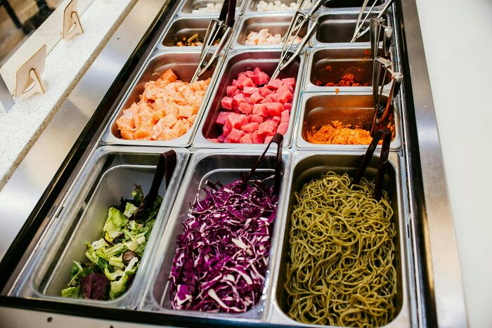 Chain restaurant salad bar with various fresh ingredients displayed in metal containers.