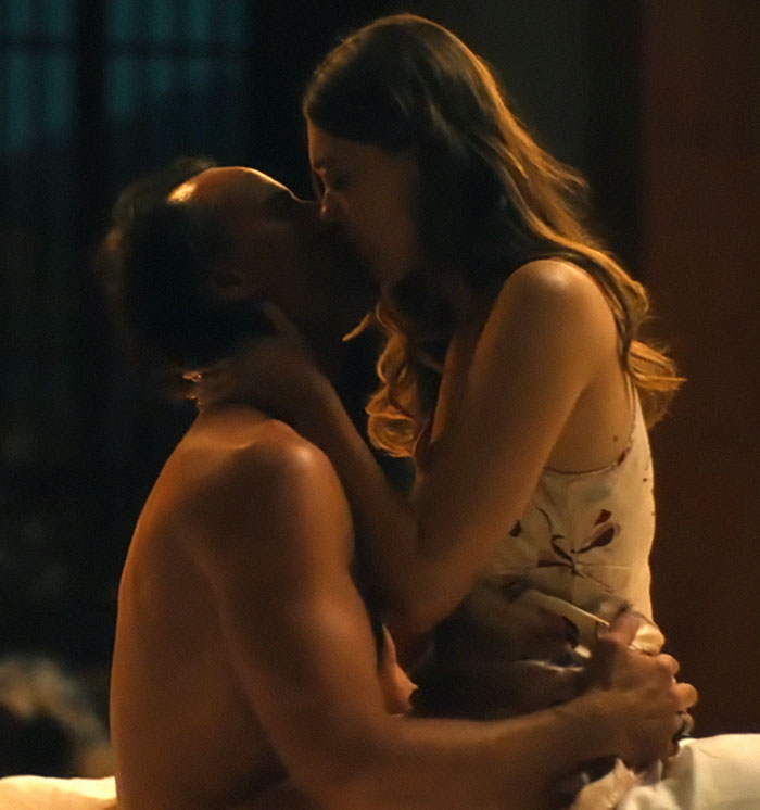 A couple intimately kissing in a dimly lit room, linked to Aimee Lou Wood's critique of a comedy skit.