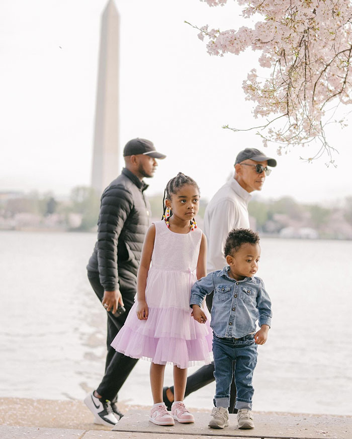 Obama photobombs kids during a photo shoot, with cherry blossoms and Washington Monument in the background.