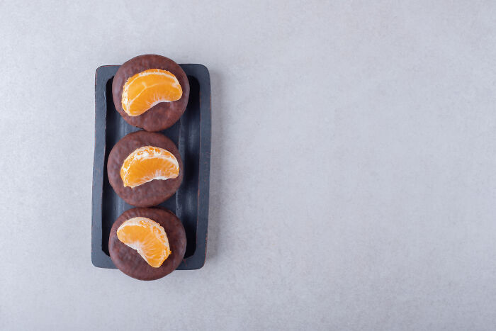 Chocolate cookies topped with tangerine slices on a black tray, illustrating a concept related to intrusive thoughts.