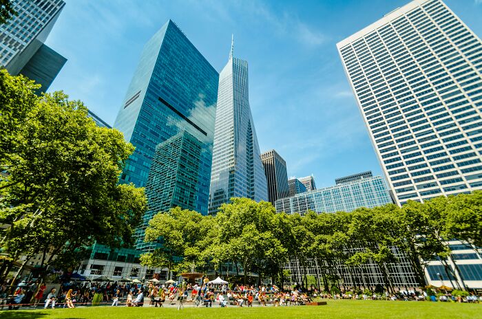 US travel destination in summer, with a park crowded by tourists and surrounded by skyscrapers under a clear blue sky.