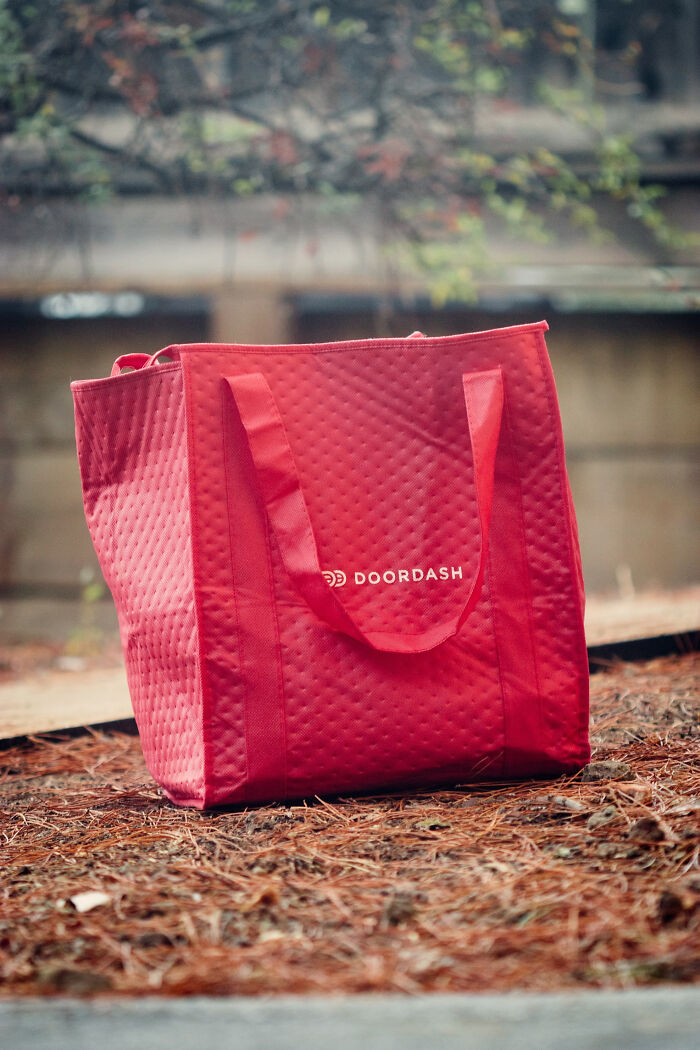 Red DoorDash delivery bag on the ground, brand loyalty concept.