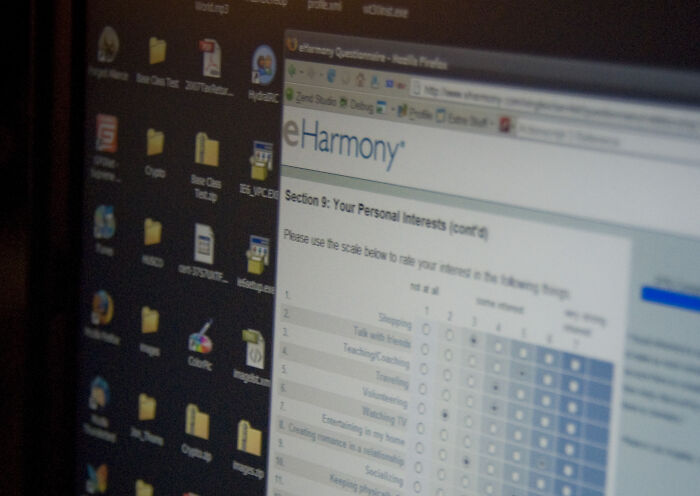 Computer screen displaying eHarmony profile questionnaire with desktop icons in view.