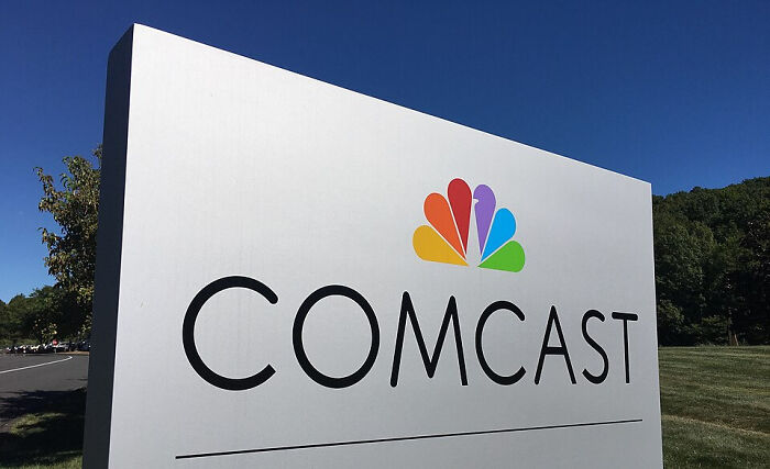 Comcast logo on a large outdoor sign against a blue sky, associated with brand loyalty discussions.