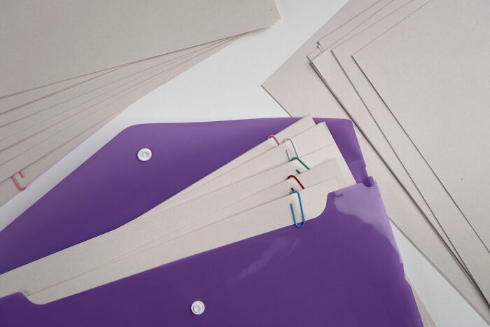 Purple folder with papers and colorful paperclips, symbolizing small things that unexpectedly saved lives.