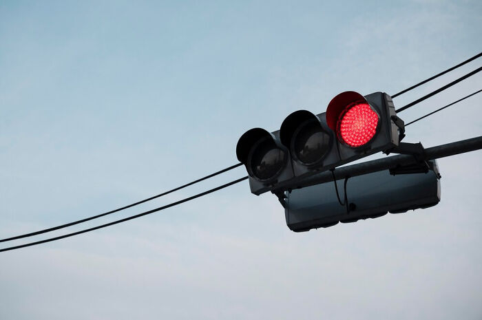 Traffic light showing red against blue sky, unexpectedly saving lives.