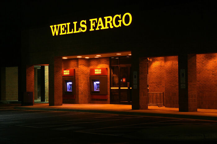 Wells Fargo bank building at night with illuminated ATMs representing companies that lost customers forever.