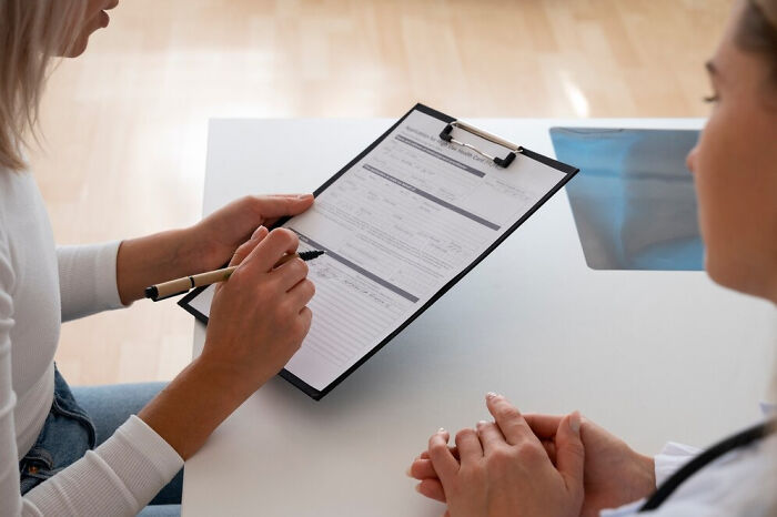 Doctor and patient discussing questions on a clipboard during a consultation.