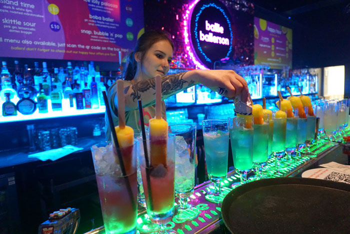 Bartender serves colorful drinks at Coachella, highlighting festival vibes amid high food prices.