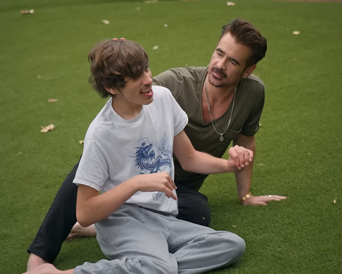 Father with his disabled son sitting on grass, sharing a moment outdoors.