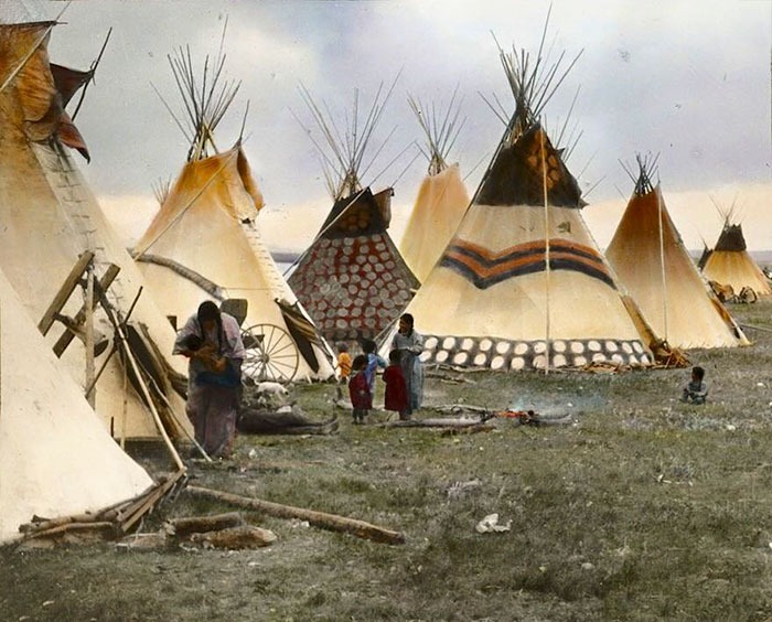 Native American teepees with families outside, depicting real lives and traditional dwellings from a century ago.