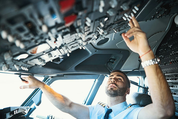 Pilot in a cockpit adjusting controls, demonstrating employee care through unique work perks.