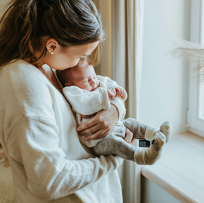 Mother embracing her newborn, illustrating caring company work perks for employees.