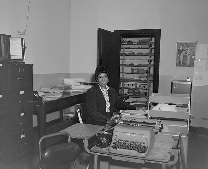 Office worker at desk with typewriter, highlighting company care through provided work perks.
