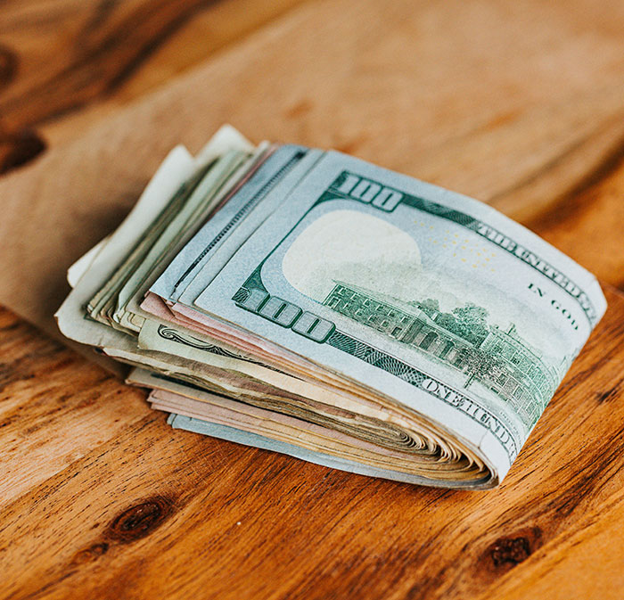 Stack of dollar bills on a wooden surface, symbolizing work perks companies offer to show employee care.